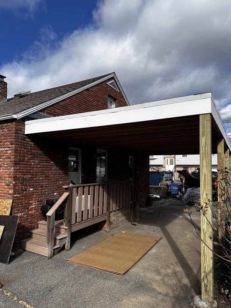 Carport cover — flat roof beam framing on brick home